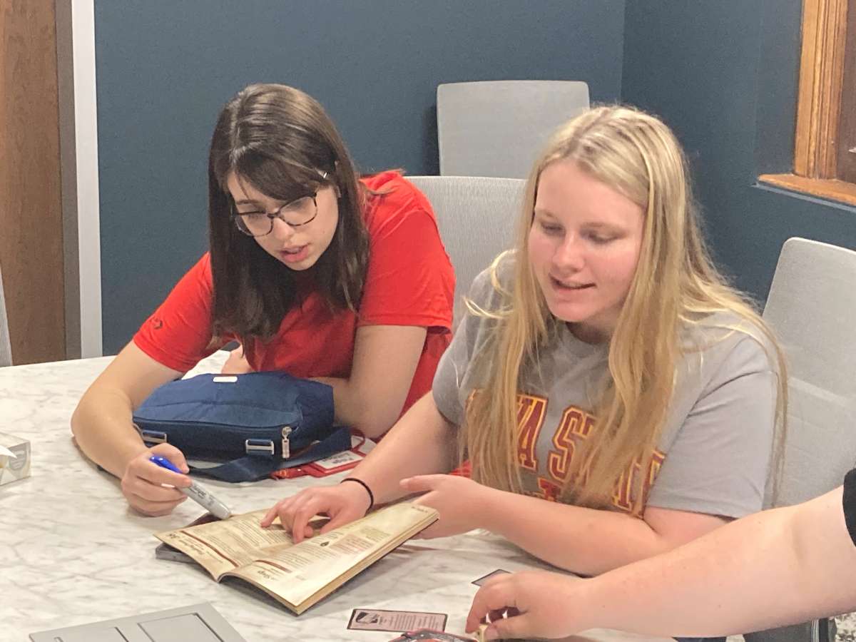 Two students look over a book together. 